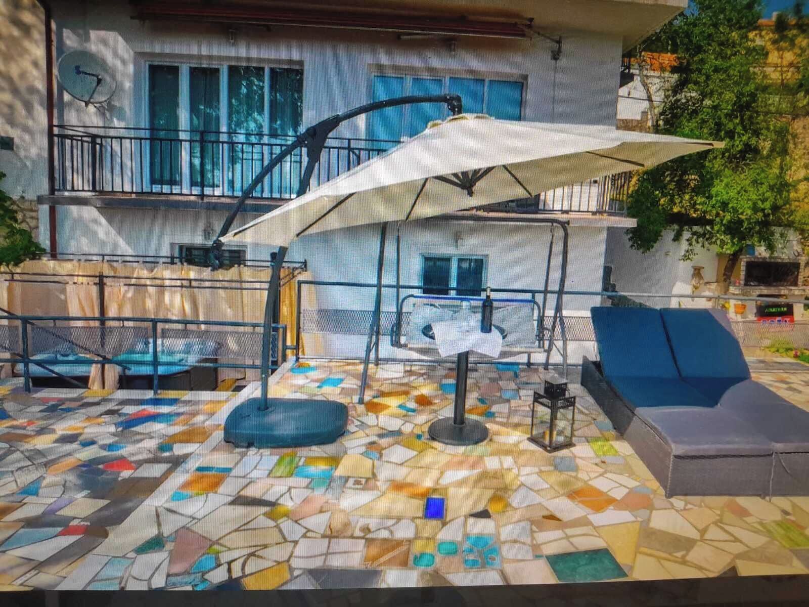 A patio with a mosaic floor, outdoor seating, and a large umbrella.