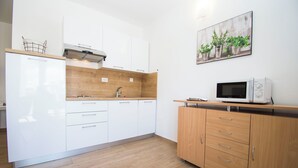 Una cucina moderna con mobili bianchi, un piano di lavoro in legno e un forno a microonde.
