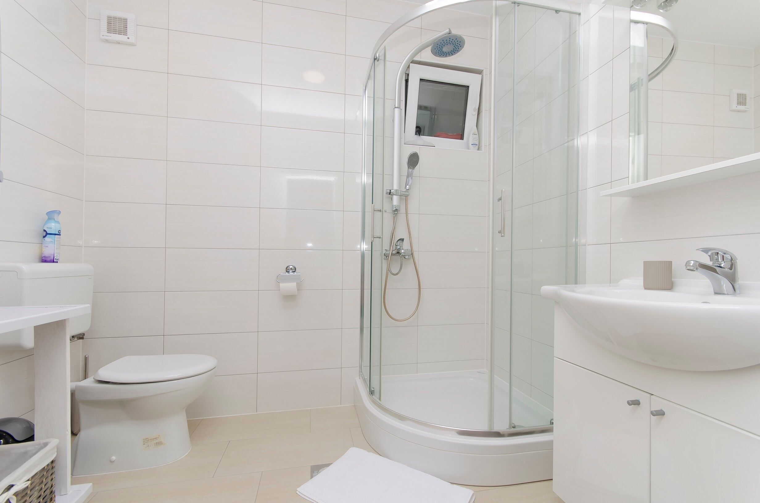A modern bathroom with a glass-enclosed shower, a toilet, and a sink.