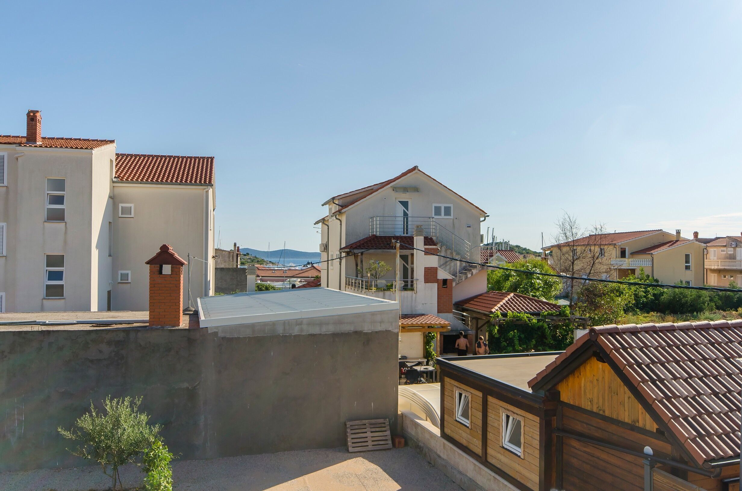 Ett bostadsområde med flera hus, inklusive en tvåvåningsbyggnad med en balkong och ett mindre envåningshus med en träfasad.