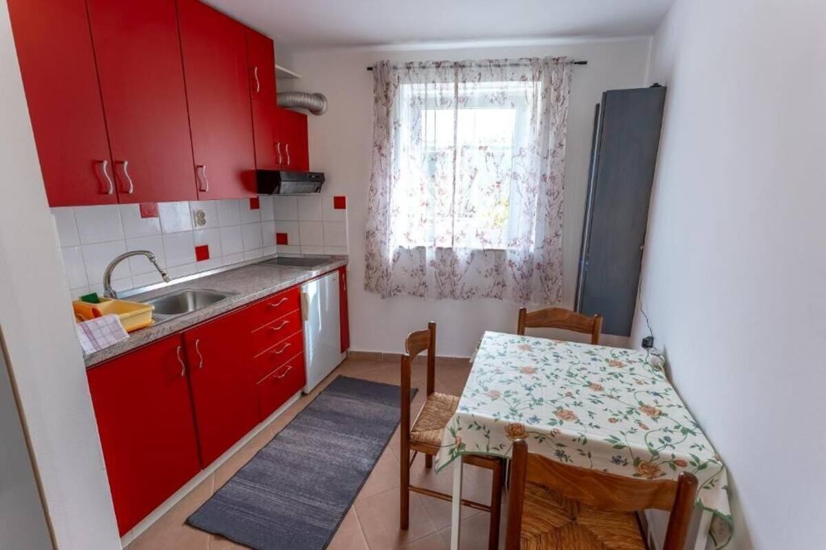 Una cocina compacta con armarios rojos, un lavamanos y una zona de comedor con una mesa y sillas.