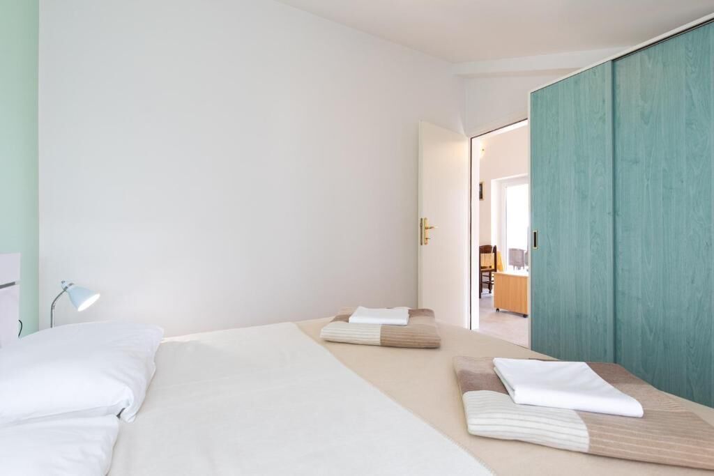 Une chambre d’hôtel avec un lit, une table de chevet, une lampe et une vue sur le couloir.