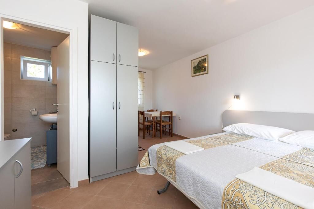 A bedroom with a bed, a wardrobe, a desk, and a chair.