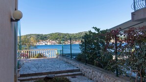 A stone-paved balcony with steps leading to a railing overlooking a body of water and a town.