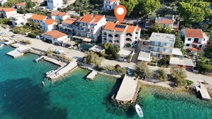 An aerial view of a coastal residential area with houses, clear turquoise water, and a marina with boats.