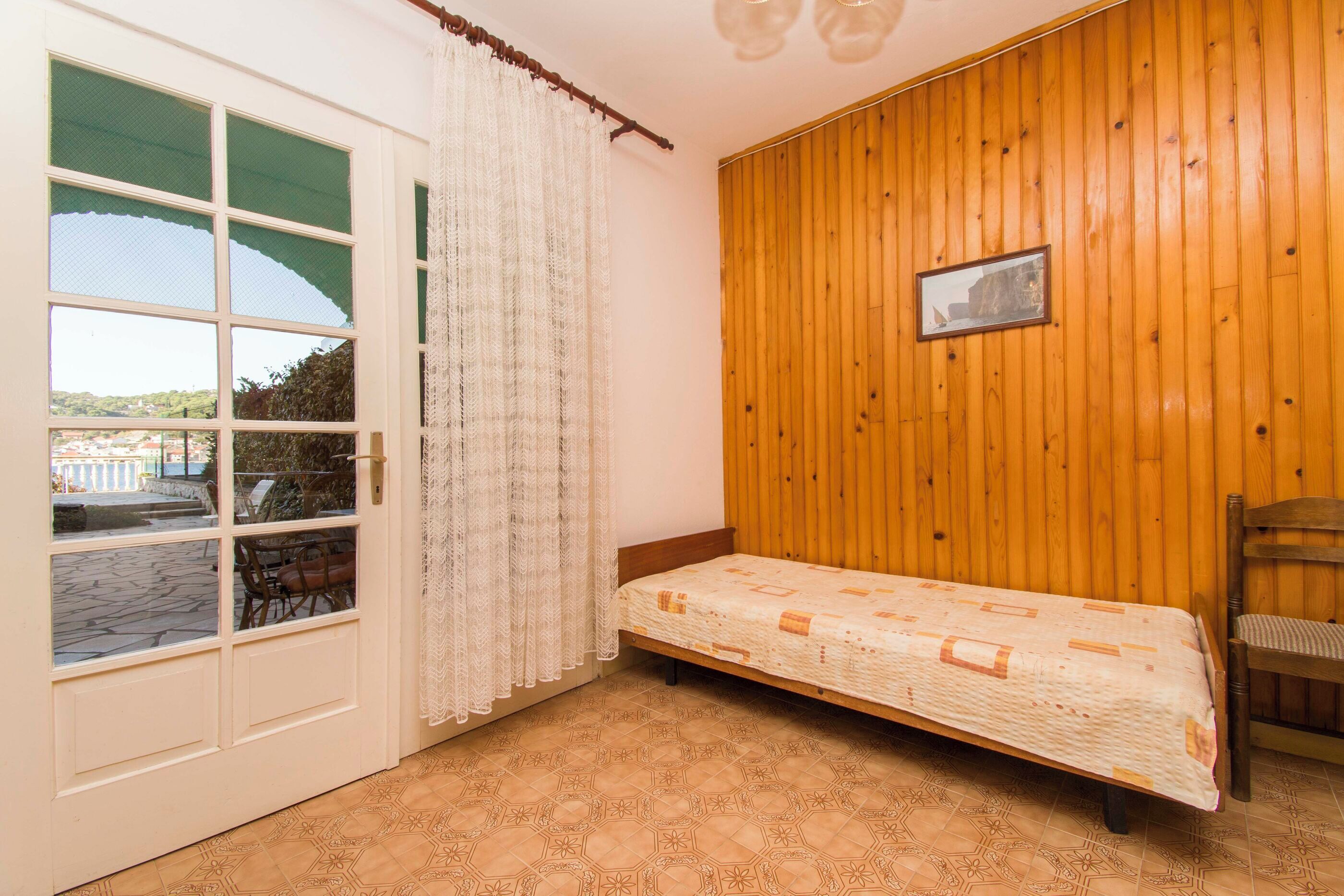 Quarto com uma cama, parede de madeira, janela com vista e uma porta.