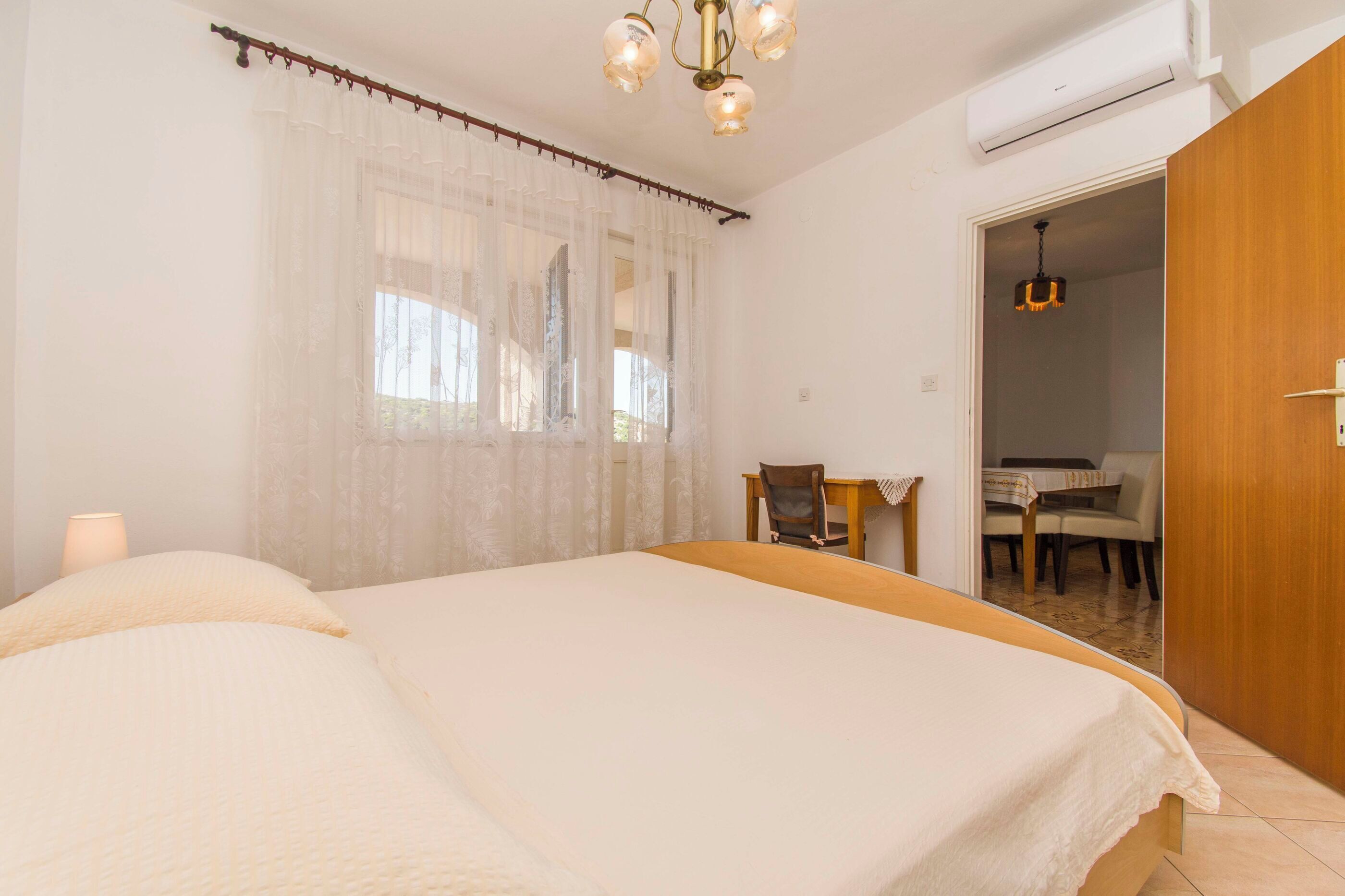 Un dormitorio con cama, una silla, una mesa y una puerta que da a un baño.