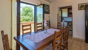 Een eetgedeelte met een houten tafel en stoelen, uitzicht op het landschap, en een keuken op de achtergrond.