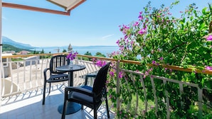 Un balcon avec une table et des chaises, offrant une vue panoramique sur les montagnes et la mer.
