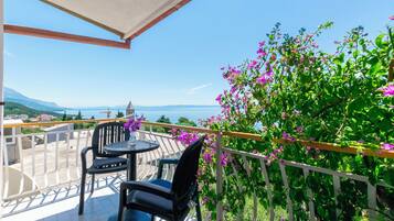 Ein Balkon mit Tisch und Stühlen, mit Blick auf eine reizvolle Berg- und Meereslandschaft.