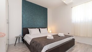 A modern hotel room with a large bed, a small side table, and a view of the city. - Apartments Neda (Bilice)