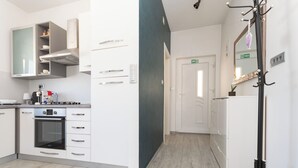 A modern kitchen with white cabinets, a built-in oven, and a black coffee machine. - Apartments Neda (Bilice)