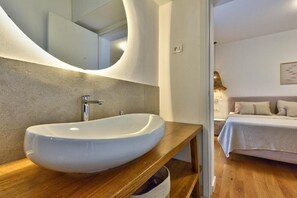 Ein modernes Badezimmer mit einem großen, ovalen Waschbecken, einer Holzabdeckung und einem gewölbten Spiegel.