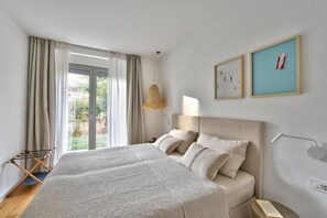 Ein Schlafzimmer mit einem großen Bett, einer Hängelampe und zwei gerahmten Bildern an der Wand.