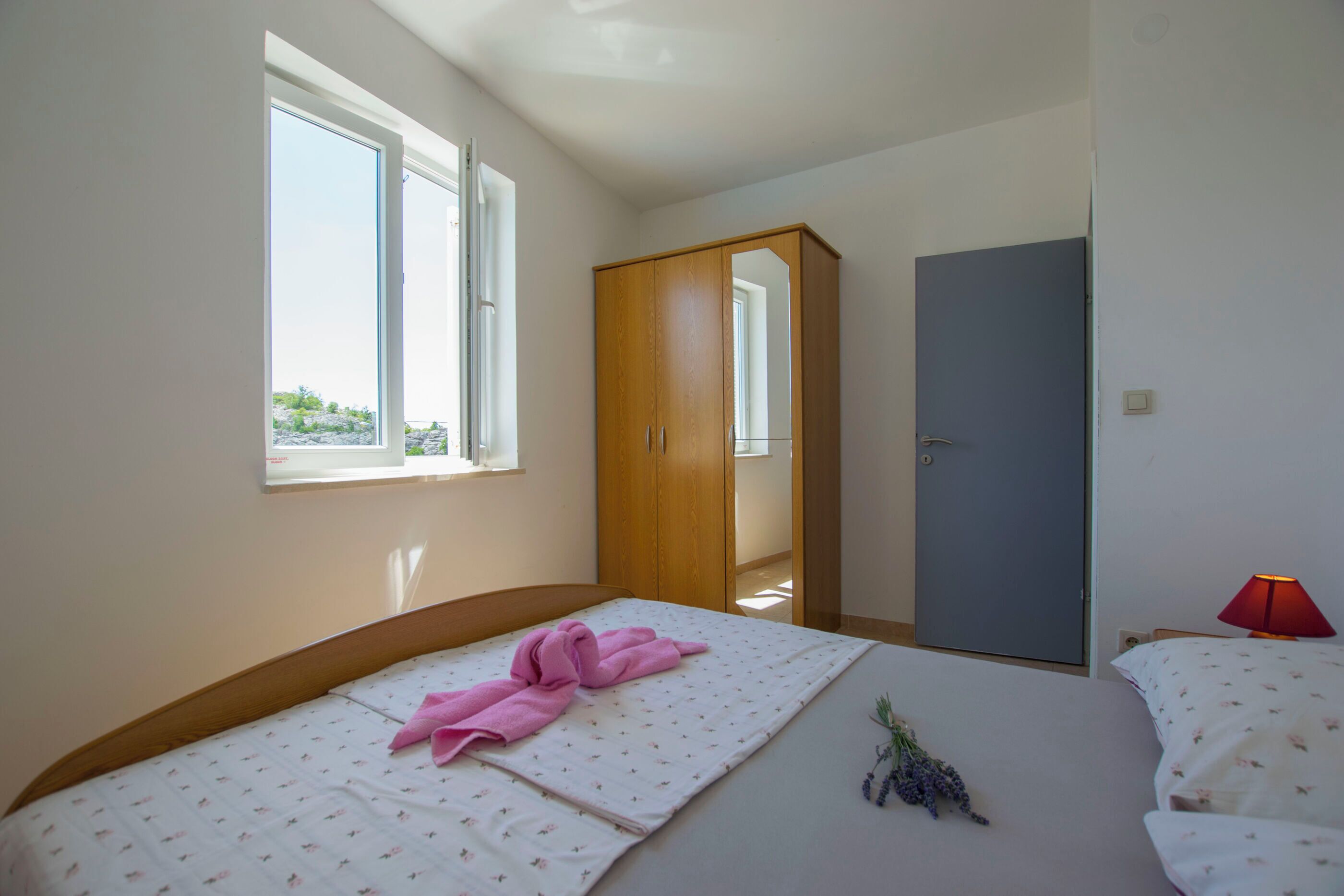Un dormitorio con cama, armario, puerta y ventana.