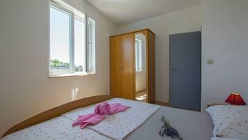 Un dormitorio con cama, armario, puerta y ventana.