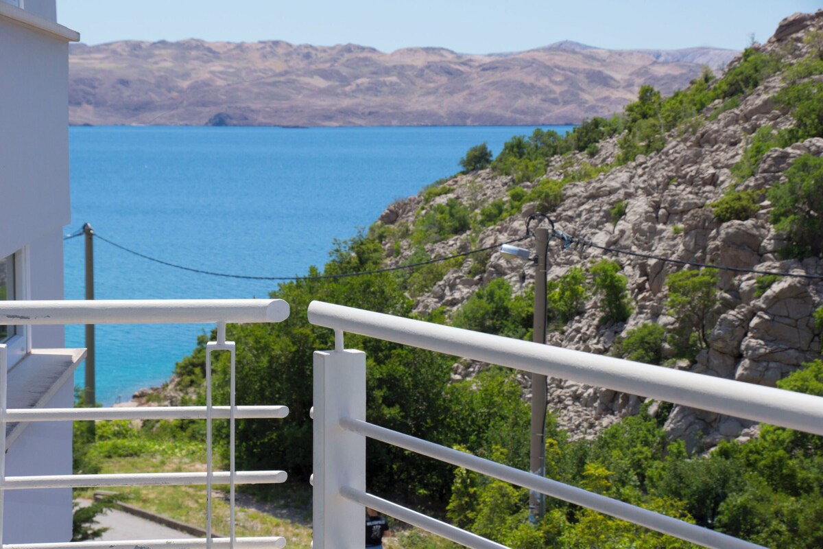 A balcony with a view of a mountainous landscape and a body of water.