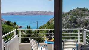 A balcony with a table, two chairs, and a bottle of wine. - Apartments Sunny (Karlobag)