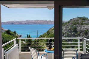 A balcony with a table, two chairs, and a bottle of wine. - Apartments Sunny (Karlobag)