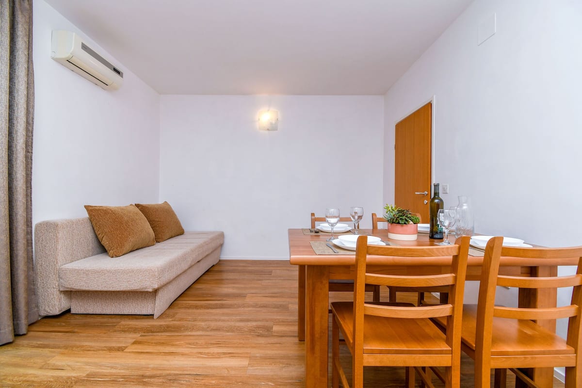 A compact living space with a sofa, dining table, and chairs.