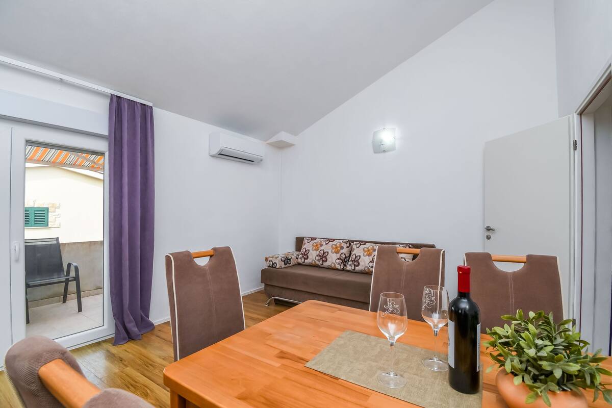 A dining area with a wooden table, chairs, a wine bottle, and a glass.