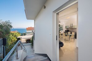 A modern apartment with a balcony overlooking the sea, a kitchen with a dining area, and a staircase leading to the upper floor. - Apartments Natasa (Seget)