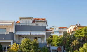 A multi-story residential building with balconies, a flat roof, and a clear sky. - Apartments Natasa (Seget)