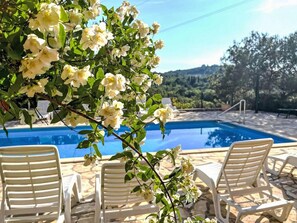 Una piscina al aire libre, sombrillas, sillones reclinables de piscina