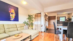 A modern living room with a sofa, a coffee table, and a dining area with a table and chairs. - Apartment Bilice (Bilice)