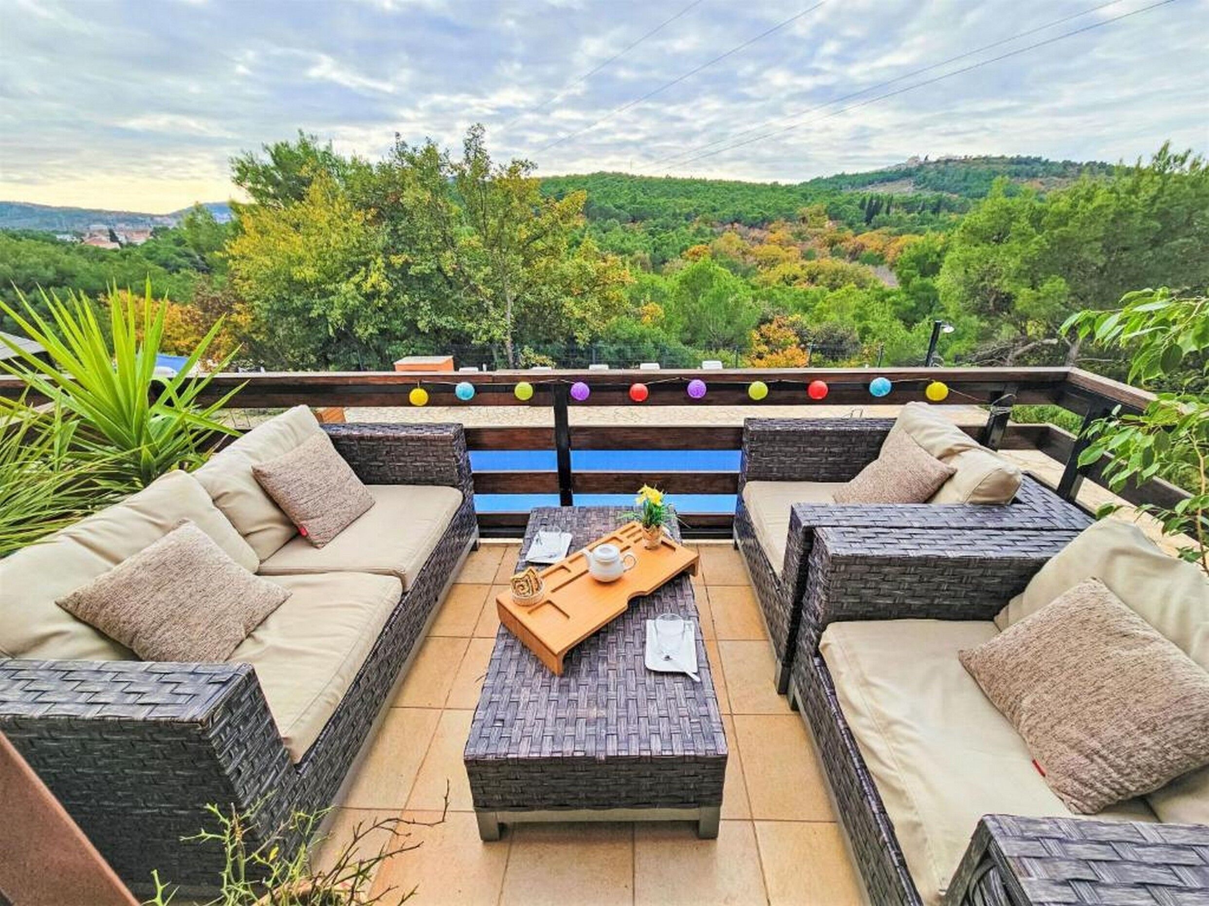 An outdoor seating area with wicker furniture and a view of a lush landscape.