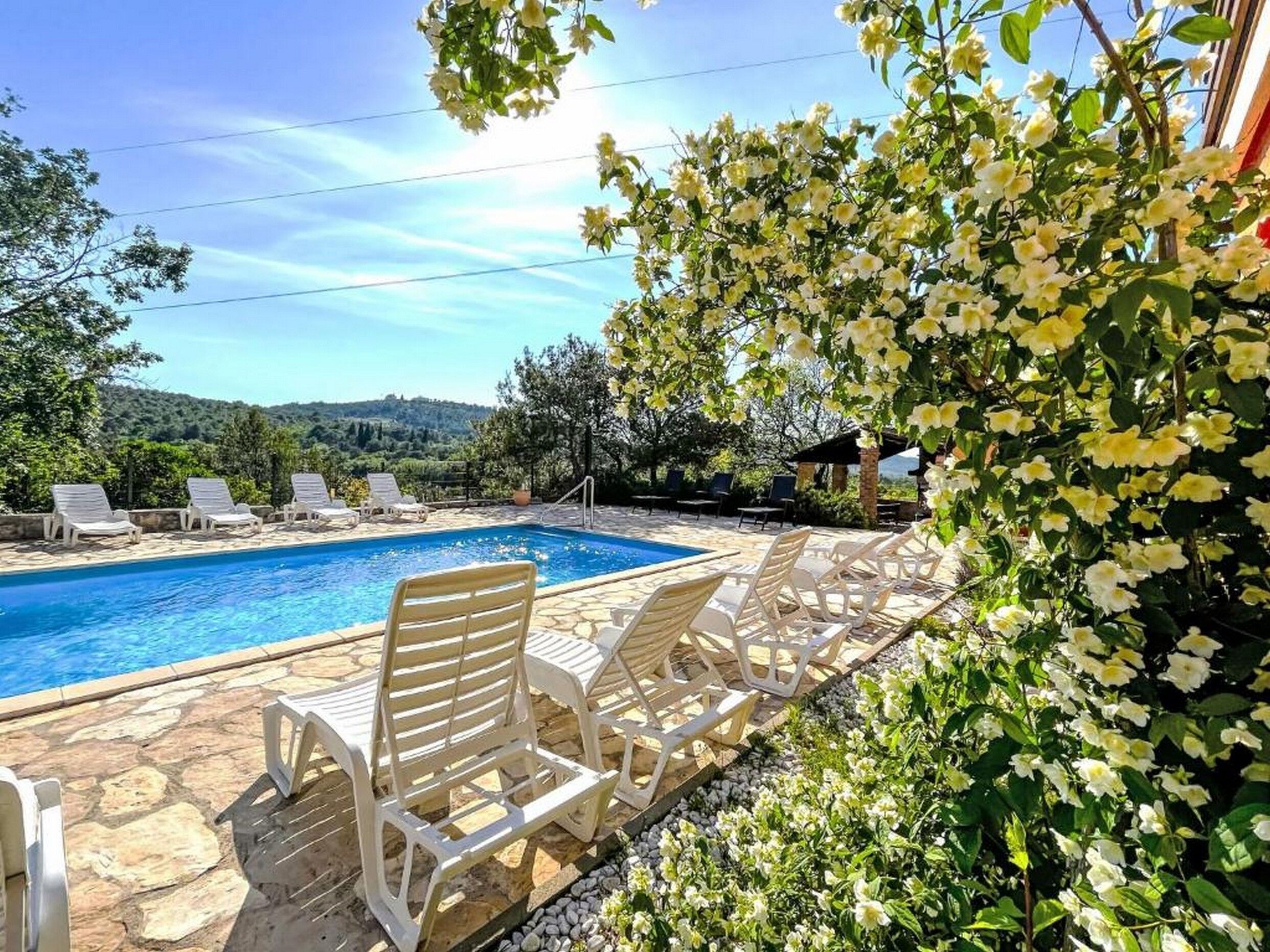 Un espace piscine doté de chaises longues et offrant une vue sur le paysage.