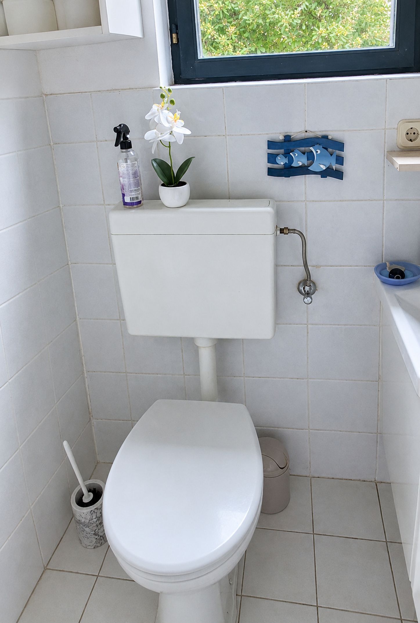 Casa de banho pequena e limpa, com sanita, lavatório e janela.