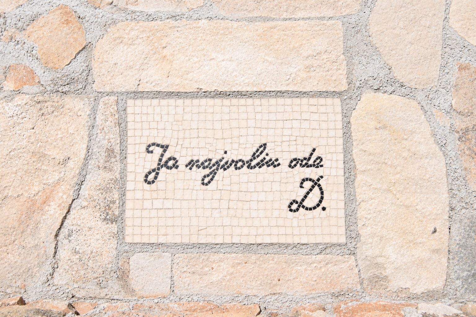 Un mosaico con scritte su una parete di pietra.