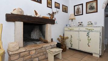 Una habitación rústica con chimenea de piedra, un banco de madera y un aparador antiguo decorado con hiedra.