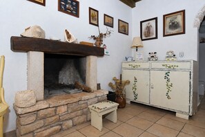 A rustic room with a stone fireplace, wooden bench, and a vintage cabinet with decorative vines. - House Darin Dvor (Vela Luka)