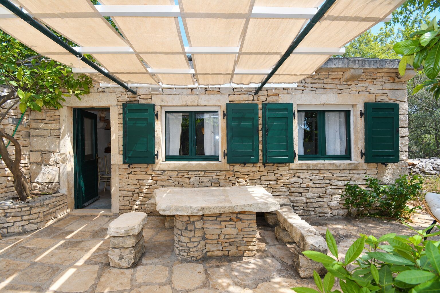 A stone building with a covered patio, a stone bench, and a door.