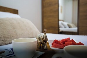 A hotel room with a bed, a cup, a small elephant figurine, and a plate of watermelon. - Apartment Molly (Rijeka)