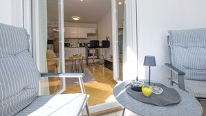 A modern living room with a glass door leading to a kitchen and dining area. There are two striped armchairs and a round table with a lamp and a tray with a glass of orange juice. - Apartment Molly (Rijeka)