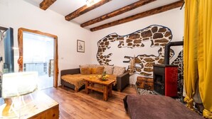 A cozy living room with a stone wall mural, wooden furniture, and a fireplace. - House Garden House (Rab)