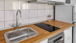 Une cuisine équipée d’un évier en acier inoxydable, d’une plaque de cuisson à induction noire et d’un four encastré.