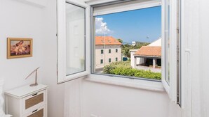 Una habitación con ventana, un tocador blanco y un cuadro en la pared.