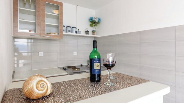 Eine Küche mit weißer Arbeitsplatte, einer grünen Weinflasche und einem Glas Rotwein.