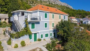 Ein mehrstöckiges Gebäude mit Balkon, Treppe und Blick auf eine gebirgige Landschaft.