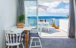 A balcony with a table and chairs, a potted plant, and a view of the sea. - House Summer Dream With Jacuzzi (Omis)