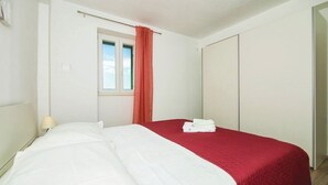 Ein Hotelzimmer mit Bett, Fenster mit Vorhang, Nachttischlampe und Kleiderschrank.