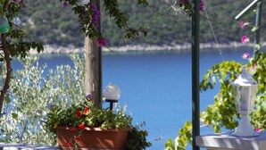 A terrace with a potted plant, a white lamp, and a view of a lake. - Apartment Kampor (Rab)