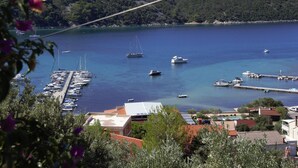 A marina with boats docked, a bridge in the background, and a hilly landscape. - Apartment Kampor (Rab)