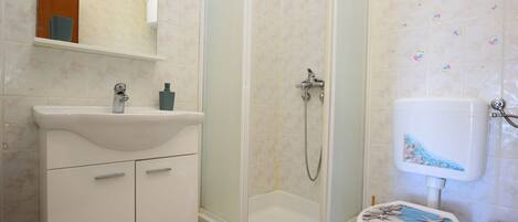 A bathroom with a shower, toilet, sink, and mirror.
