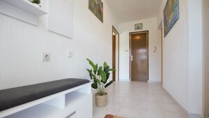 A hallway with a bench, a potted plant, and a door at the end. - Apartment Kampor (Rab)