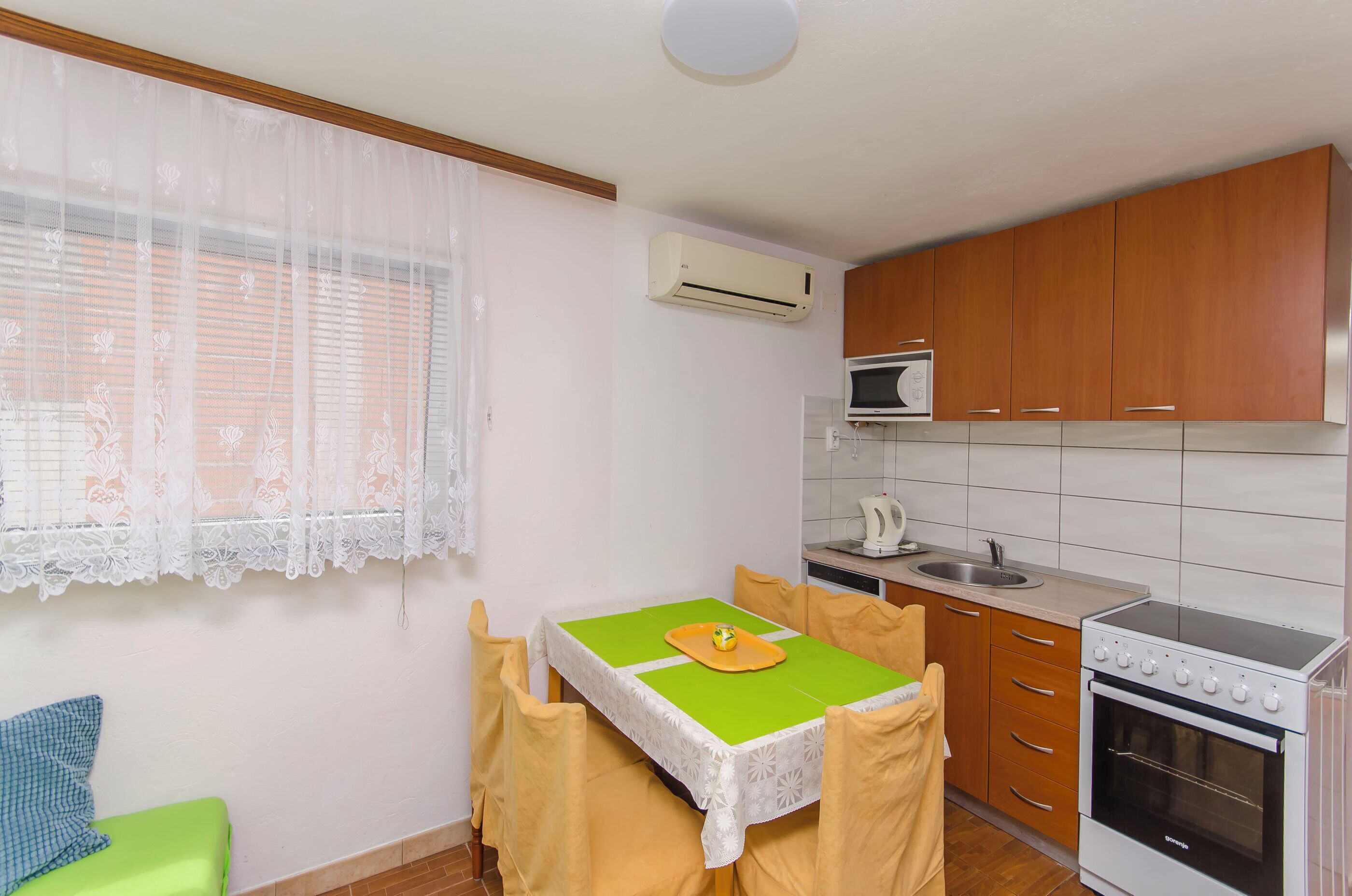 Une cuisine compacte comprenant une table à manger, un four à micro-ondes, une cuisinière et un évier.